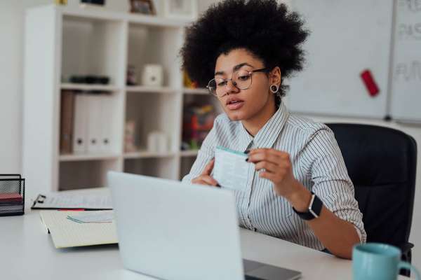 Virtual Classroom. Young afro american female teacher explaining something while teaching through webcam at home. Sitting at her workplace and looking at camera. E-learning. Distance education