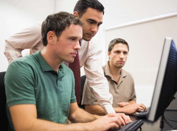 Concentrated,Teacher,With,Mature,Students,Using,Computer,In,The,Computer Concentrated teacher with mature students using computer in the computer room